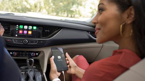 Mujer en un auto accediendo a CarPlay desde un teléfono inteligente