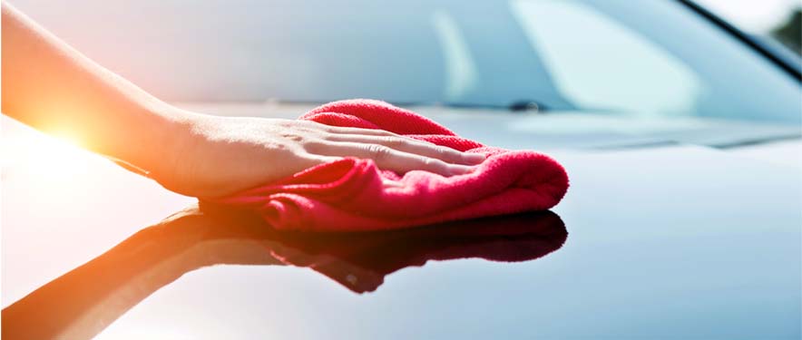 Person polishing the hood of their car with red cloth
