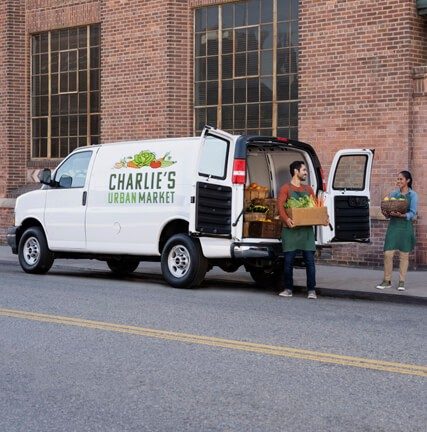 Small business owners standing next to Chevrolet white van