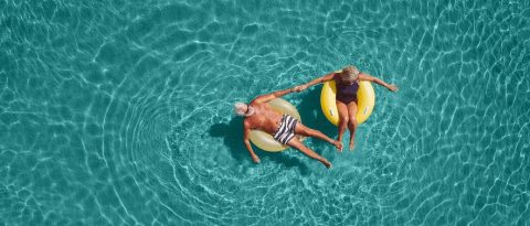 From above, relaxed mature couple floating in the sea.