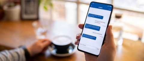 Person chatting with GM Financial’s virtual assistant, Nanci, on their phone while having coffee.
