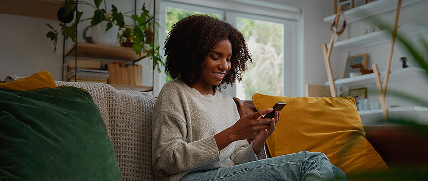 Happy woman researching car insurance in her stylish apartment while relaxing on her sofa.