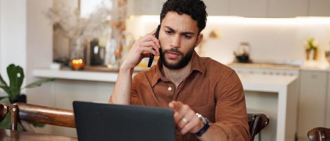Pensive man reading insurance information on a laptop.